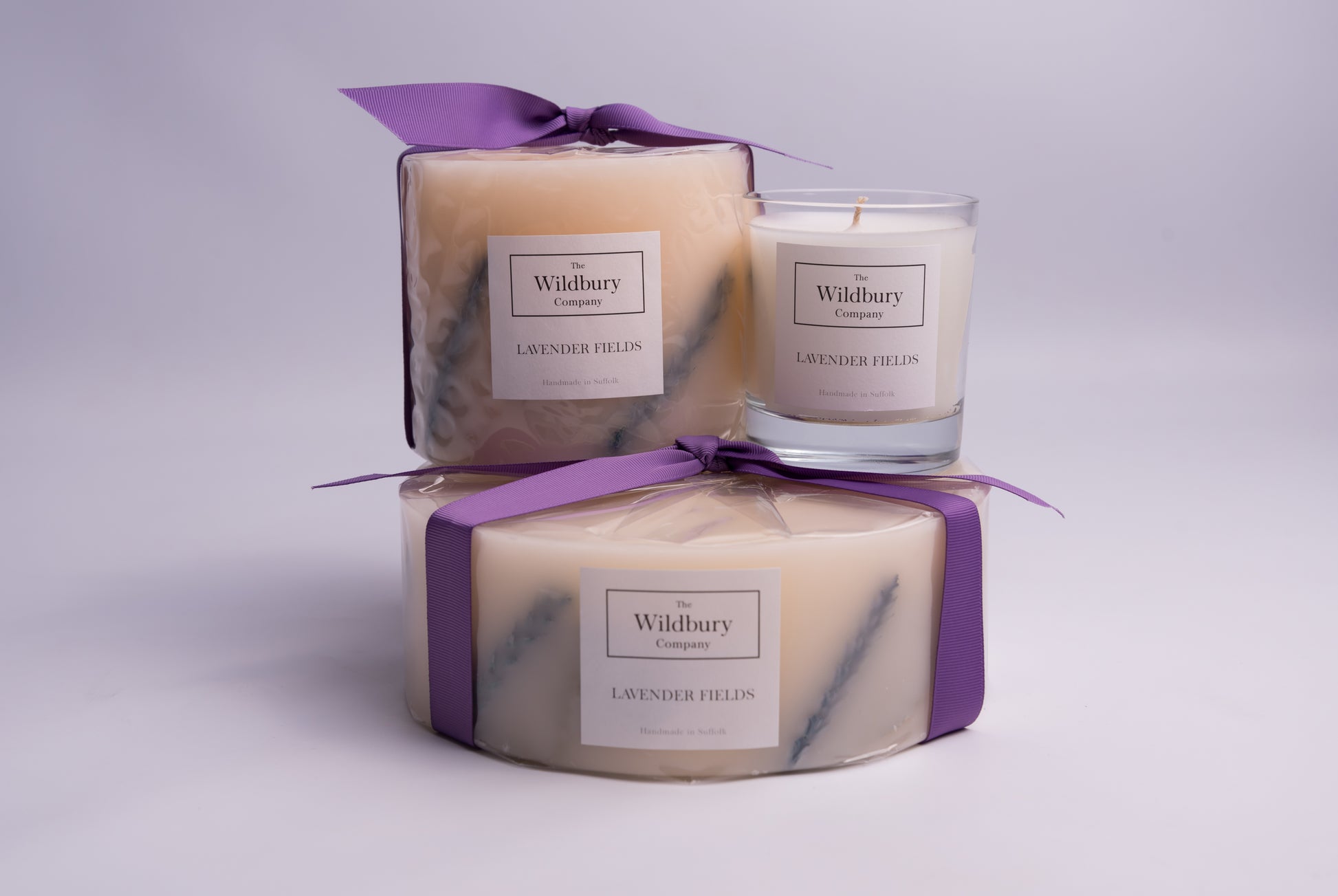 Collection of three Lavender Fields candles stacked, in three sizes with purple ribbon