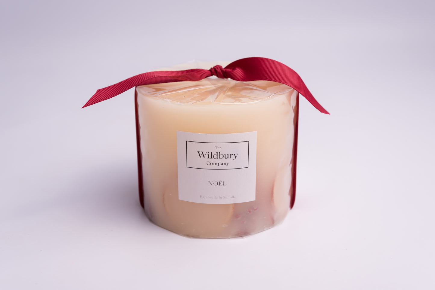 Large Three Wiick Botanical Candle with orange slices, cinnamon sticks, pepper berries and fir tips carefully suspended within the wax, tied with red ribbon.