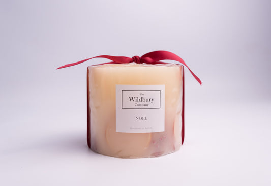Large Three Wiick Botanical Candle with orange slices, cinnamon sticks, pepper berries and fir tips carefully suspended within the hand-poured wax, Tied with a red Ribbon.