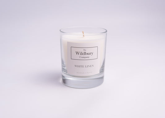 Single Wick White Candle in glass with a label detailing the logo of The Wildbury Company and candle fragrance White Linen